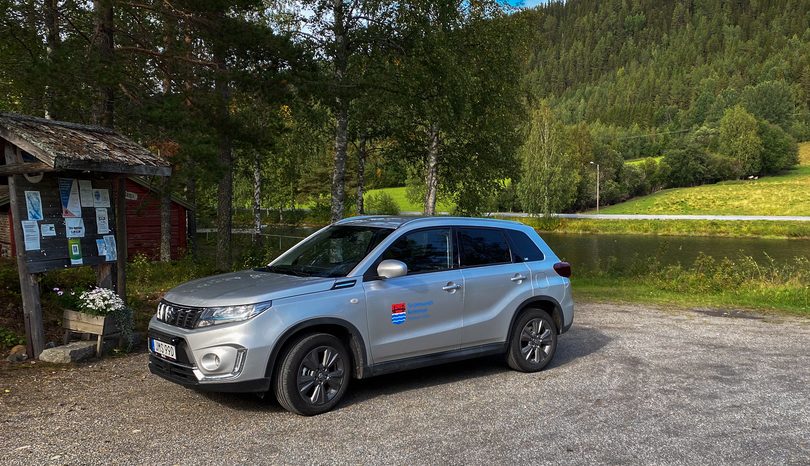 Parkerad bil. I bakgrunden skog och en sjö.