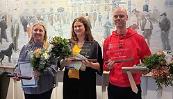 Tre personer med blommor och diplom.